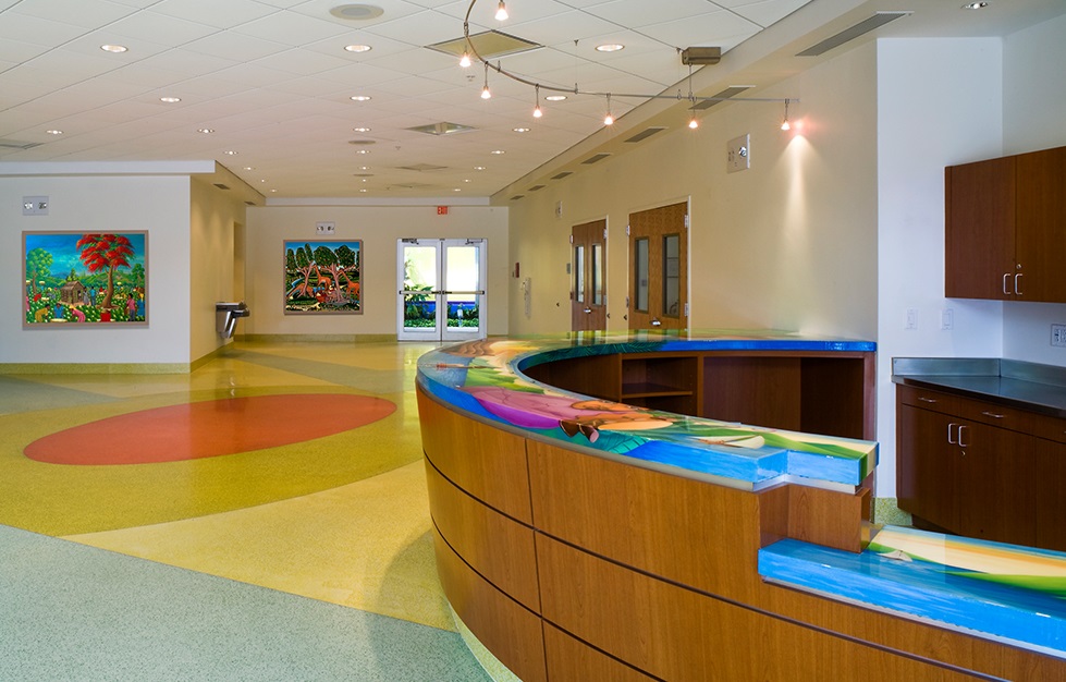 A lobby with a desk and art on the walls and a colorful floor